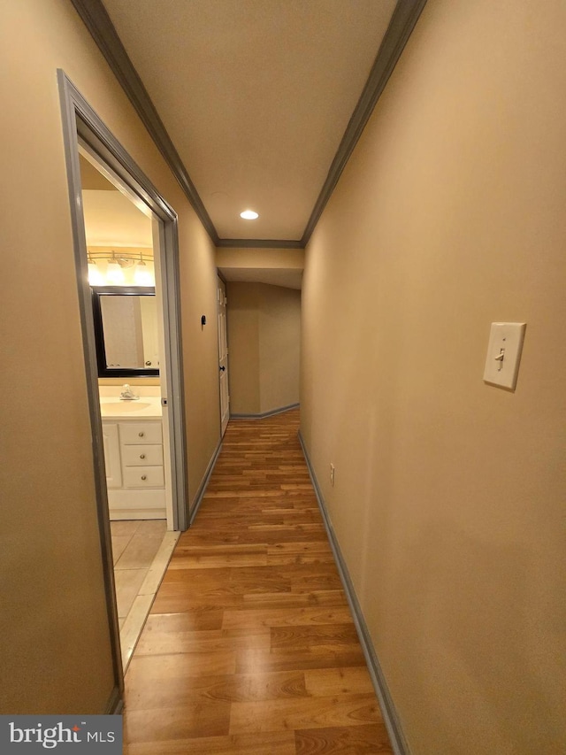 hall with crown molding, sink, and light wood-type flooring