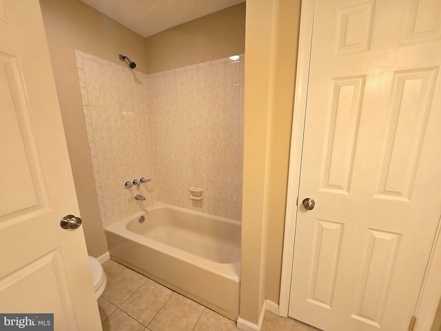 bathroom with tile patterned flooring, toilet, and tiled shower / bath