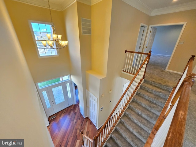 interior space featuring crown molding, wood-type flooring, a chandelier, and a high ceiling