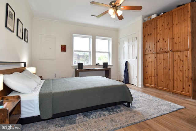 bedroom with ceiling fan, light wood-type flooring, a closet, and crown molding