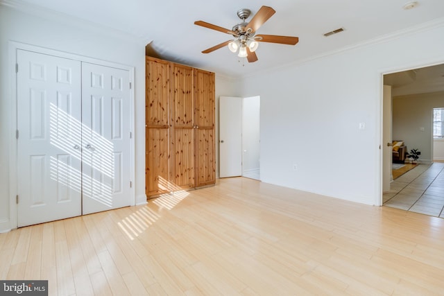 empty room with light wood-type flooring, ceiling fan, and crown molding