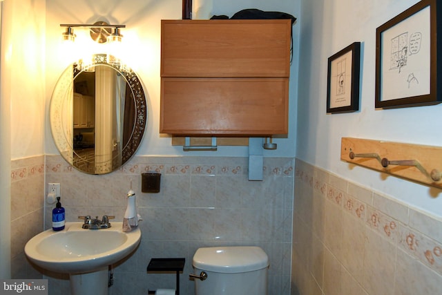 bathroom with sink, tile walls, and toilet