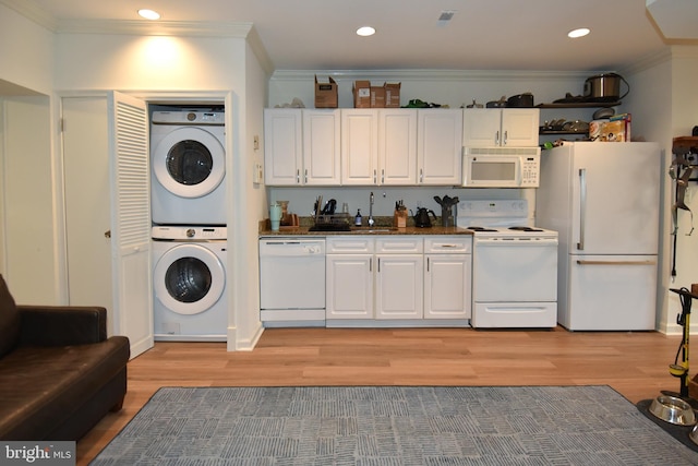 kitchen featuring crown molding, stacked washer / dryer, white cabinets, and white appliances