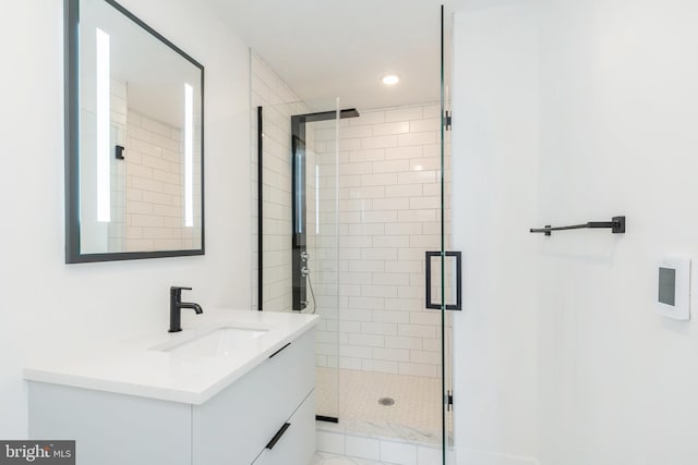 bathroom featuring a shower with door and vanity