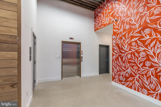 hallway featuring a high ceiling and elevator