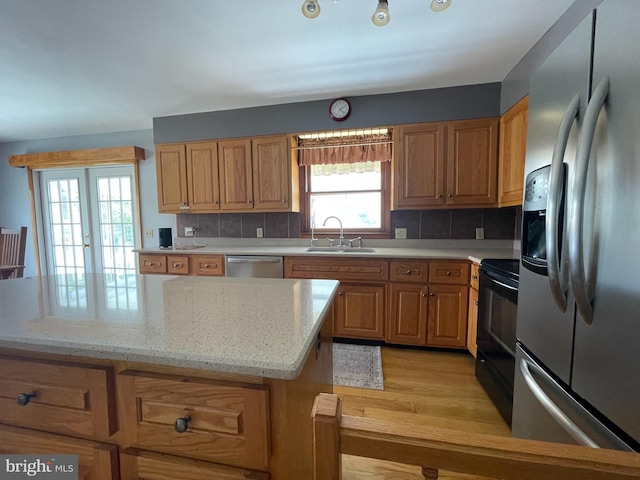 kitchen featuring sink, light hardwood / wood-style flooring, stainless steel appliances, and tasteful backsplash