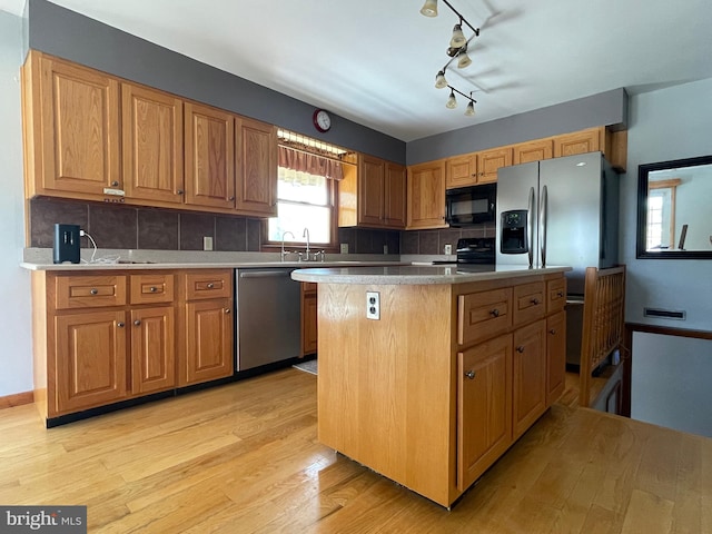 kitchen with backsplash, light hardwood / wood-style flooring, a center island, and black appliances