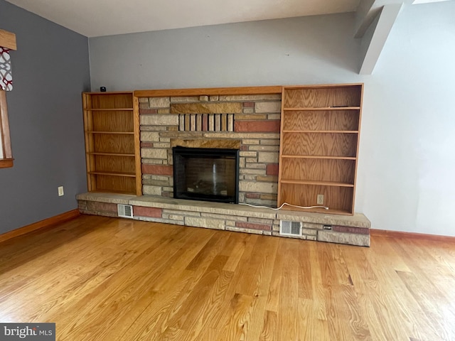 unfurnished living room with light hardwood / wood-style floors and a stone fireplace