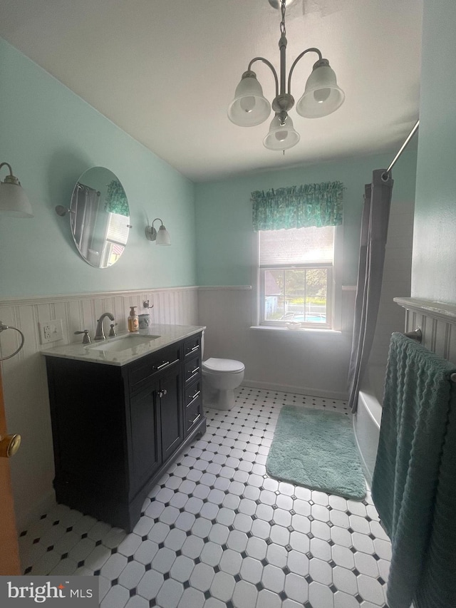 full bathroom featuring an inviting chandelier, shower / bath combination with curtain, vanity, and toilet