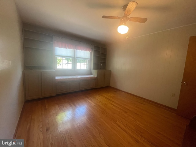 empty room featuring light wood-type flooring, ceiling fan, and built in features