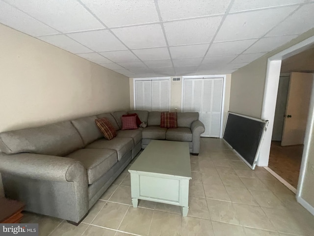 tiled living room with a paneled ceiling