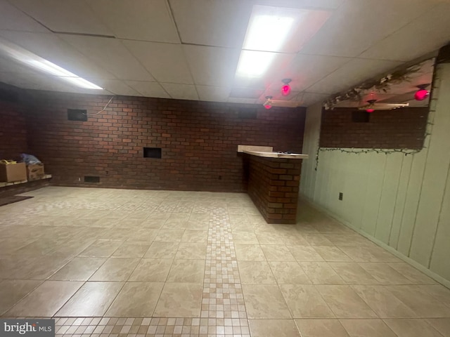 basement with a paneled ceiling and light tile patterned floors