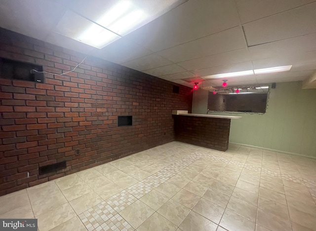 basement featuring brick wall and light tile patterned flooring