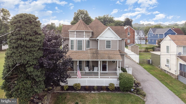 victorian home with a porch, cooling unit, and a front lawn