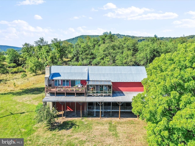 back of property featuring metal roof, a yard, a chimney, and a wooded view