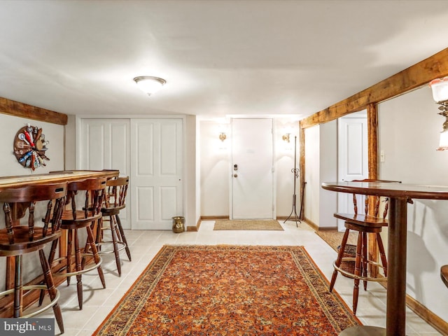 foyer with baseboards, light tile patterned floors, and a dry bar