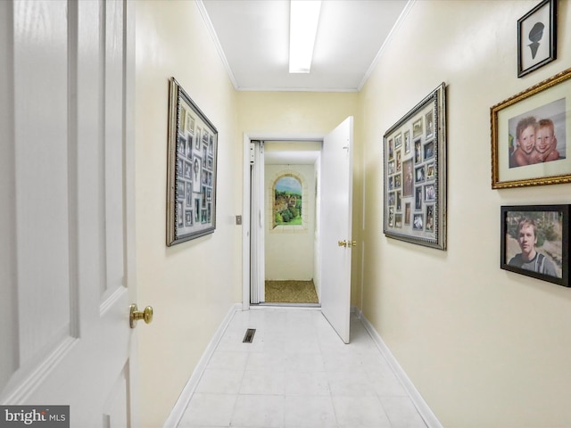 hall with visible vents, ornamental molding, and baseboards