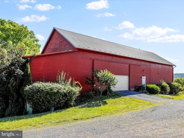 exterior space with metal roof, a detached garage, and an outbuilding