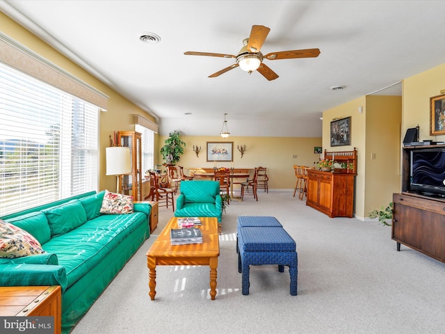 carpeted living room featuring baseboards, visible vents, and ceiling fan