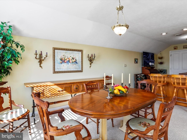 dining room with light colored carpet and vaulted ceiling