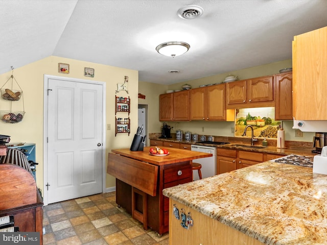 kitchen featuring a sink, visible vents, stone finish floor, wooden counters, and dishwasher