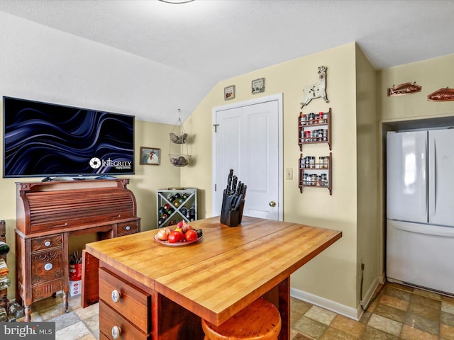dining area with stone finish floor, vaulted ceiling, and baseboards
