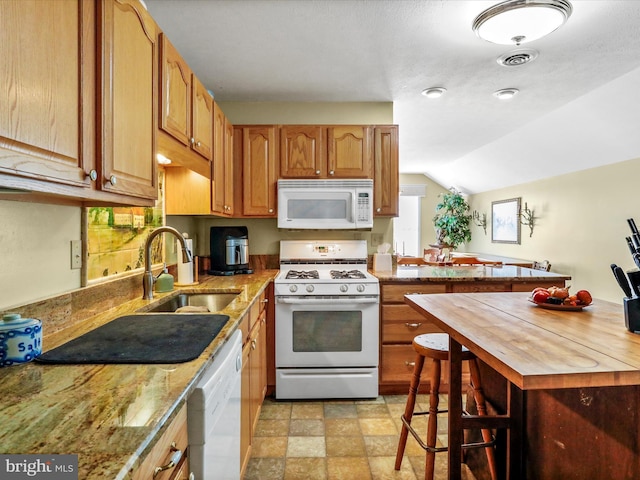 kitchen featuring white appliances, wooden counters, stone finish flooring, a sink, and visible vents