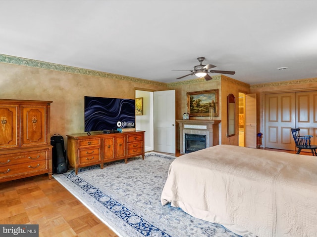 bedroom featuring a ceiling fan and a glass covered fireplace