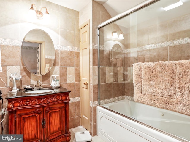 bathroom with vanity, tile walls, and combined bath / shower with glass door
