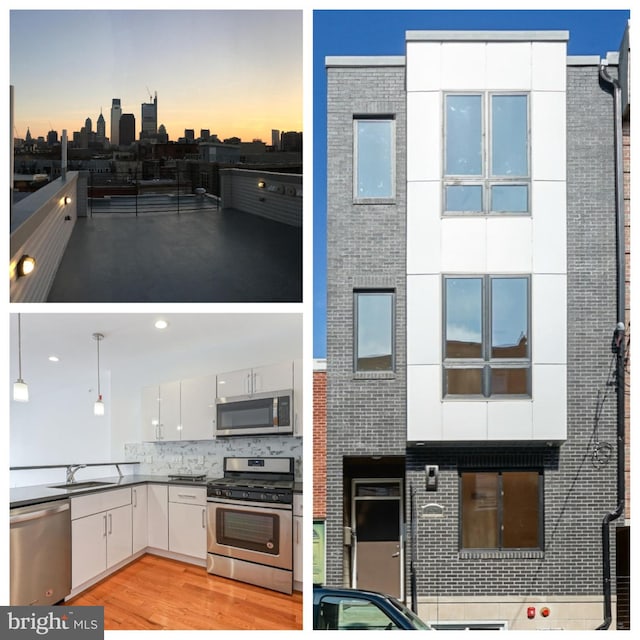 exterior space with tasteful backsplash, stainless steel appliances, sink, pendant lighting, and light wood-type flooring