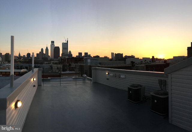 patio terrace at dusk featuring central AC and a balcony