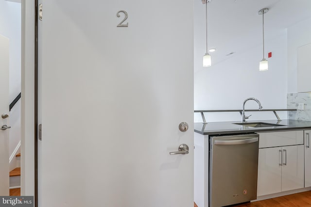 kitchen featuring sink, white cabinetry, hanging light fixtures, light hardwood / wood-style flooring, and stainless steel dishwasher