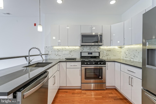 kitchen with sink, backsplash, hanging light fixtures, stainless steel appliances, and white cabinets