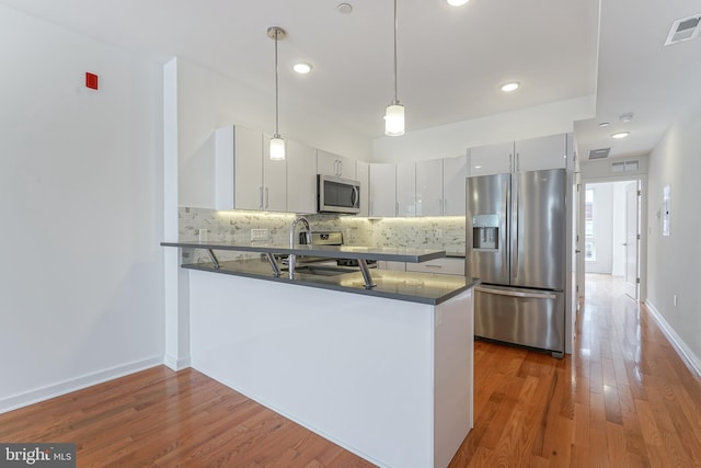 kitchen featuring white cabinetry, appliances with stainless steel finishes, pendant lighting, and kitchen peninsula