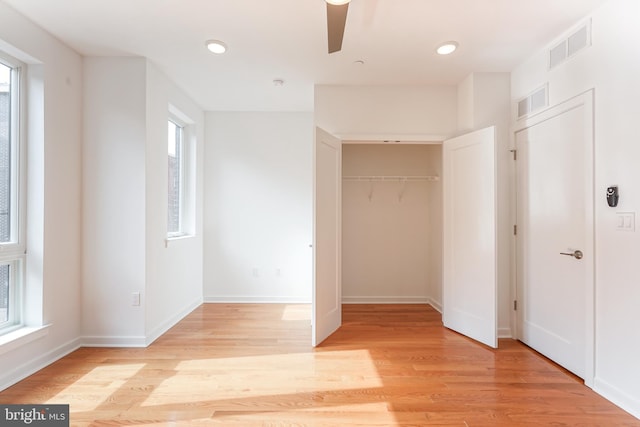 unfurnished bedroom with ceiling fan, a closet, and light wood-type flooring