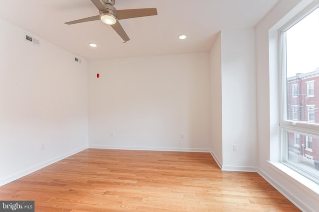 spare room with light hardwood / wood-style flooring, a wealth of natural light, and ceiling fan