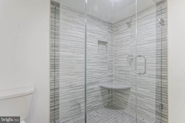 bathroom with a shower with door and toilet