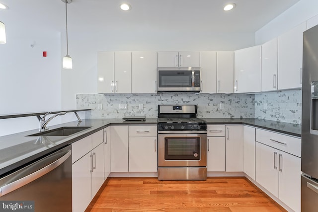 kitchen with white cabinetry, appliances with stainless steel finishes, and hanging light fixtures