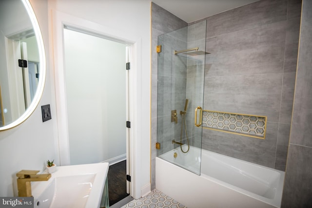 bathroom with sink and bath / shower combo with glass door