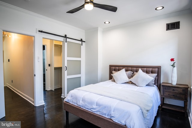 bedroom with crown molding, a barn door, dark wood-type flooring, and ceiling fan