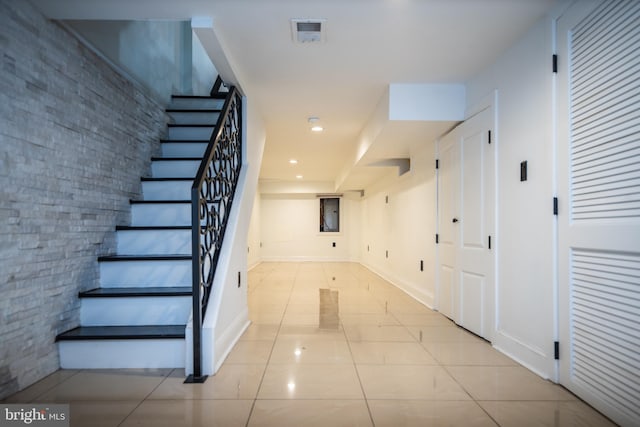 stairs featuring brick wall and tile patterned floors