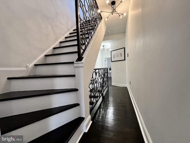 stairway with hardwood / wood-style floors and a chandelier