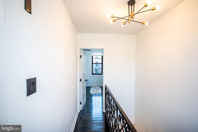 hallway featuring an inviting chandelier and dark wood-type flooring