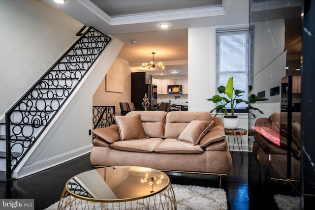 living room featuring a notable chandelier, dark wood-type flooring, ornamental molding, and a raised ceiling