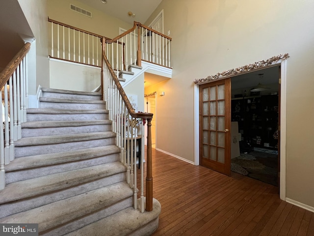 stairway featuring hardwood / wood-style floors and a high ceiling