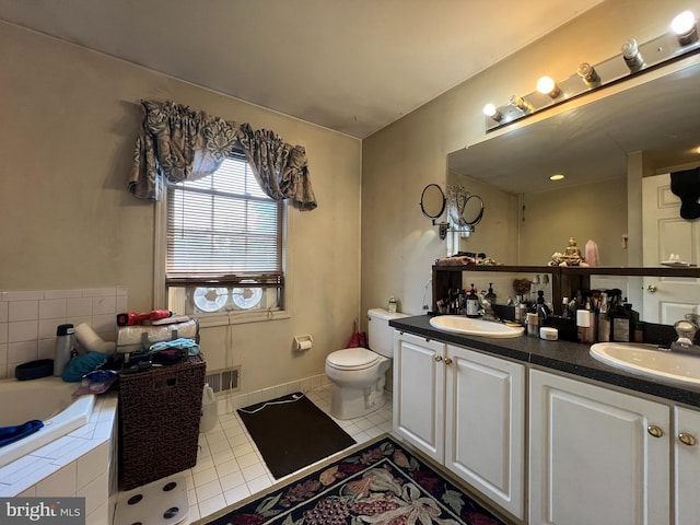 bathroom featuring vanity, toilet, tile patterned flooring, and tiled tub