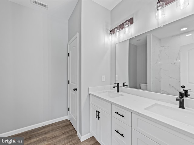 bathroom with hardwood / wood-style floors, toilet, and dual bowl vanity