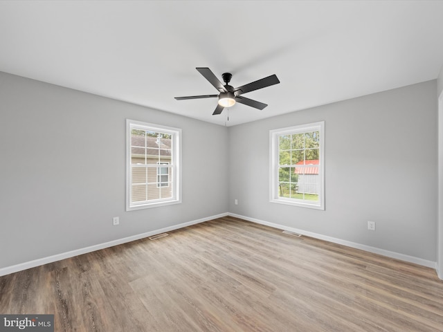 spare room featuring ceiling fan, wood-type flooring, and plenty of natural light