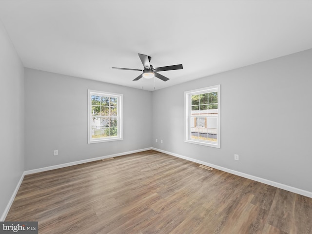 empty room featuring wood-type flooring, ceiling fan, and a healthy amount of sunlight