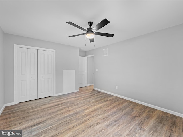 unfurnished bedroom featuring a closet, hardwood / wood-style floors, and ceiling fan